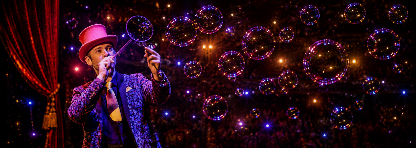 Allan Hart soufflant des bulles de savon sur scène lors de son spectacle